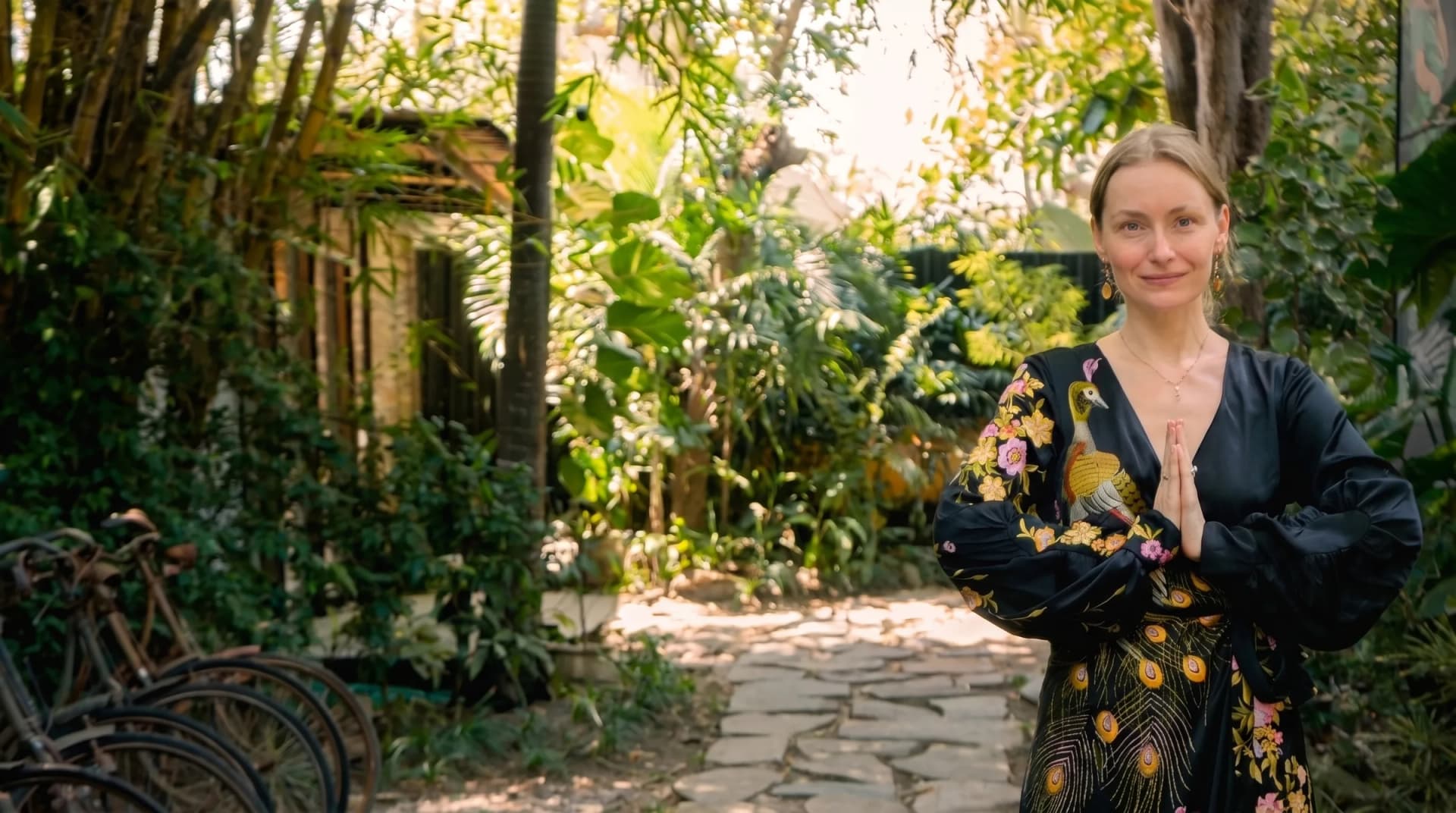 Alina Avdyukova standing with her hands at her heart in a garden in Bali