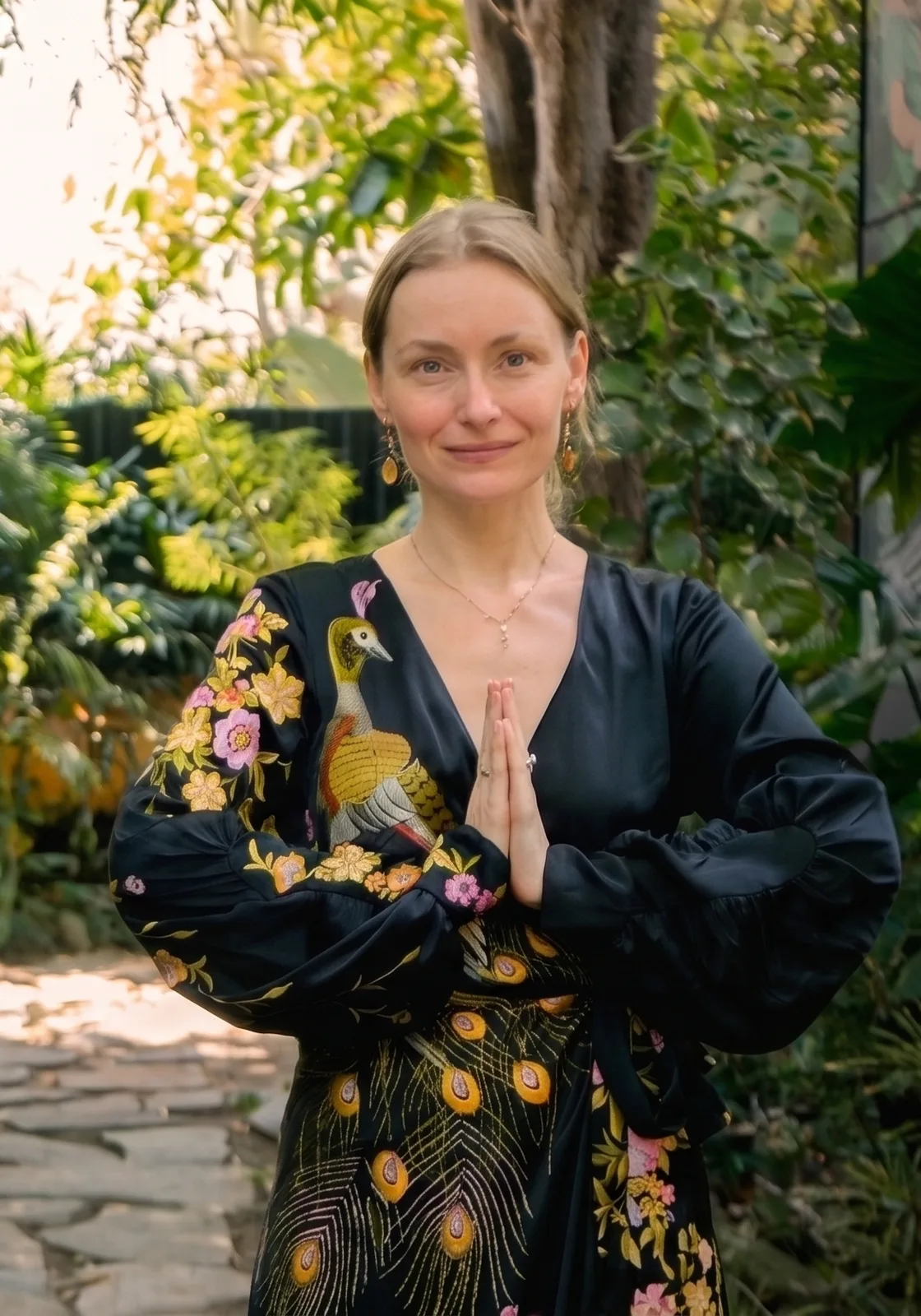 Alina Avdyukova standing with her hands at her heart in a garden in Bali