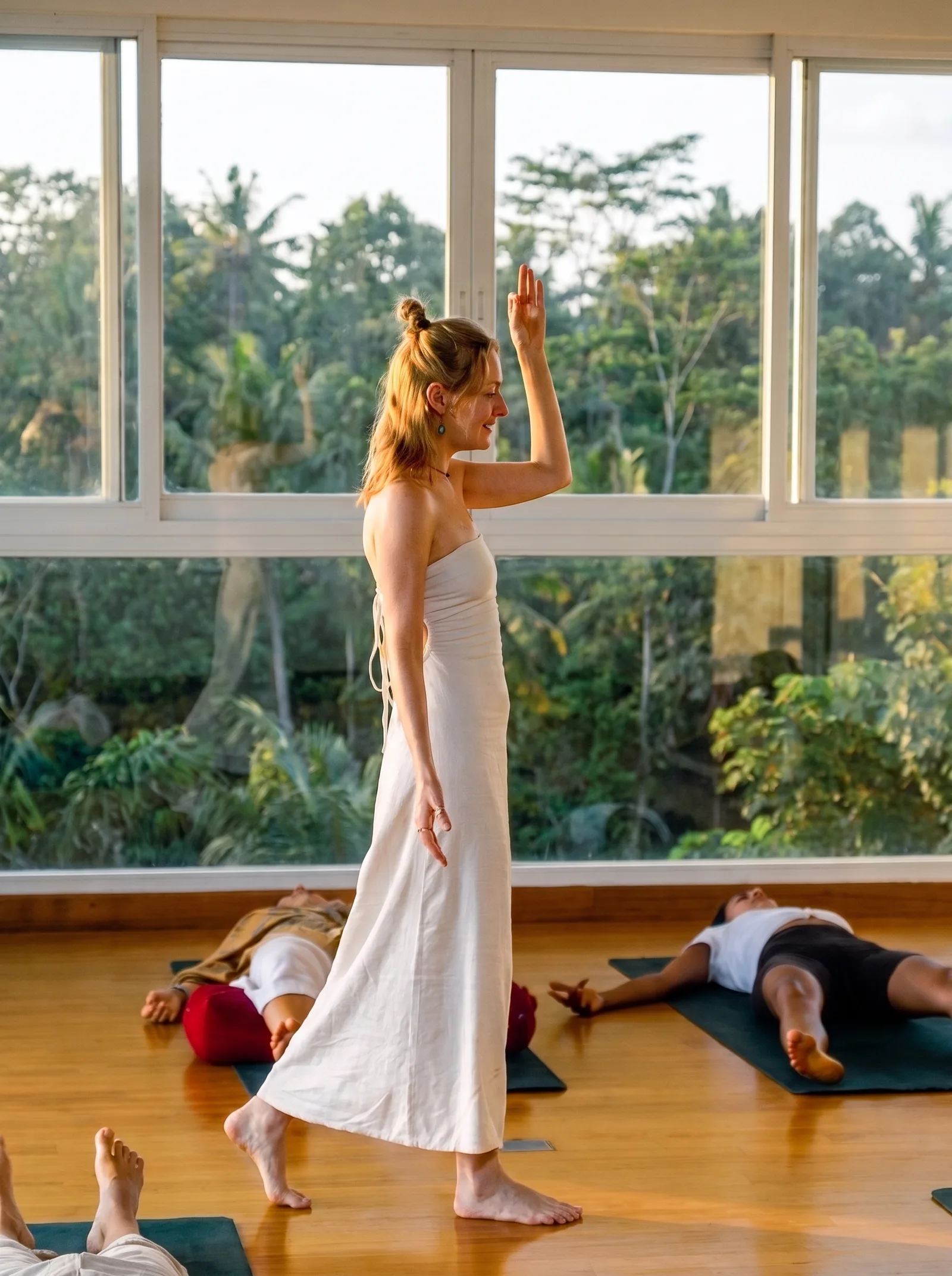 Alina walking between participants lying on mats in the golden light of a Bali studio