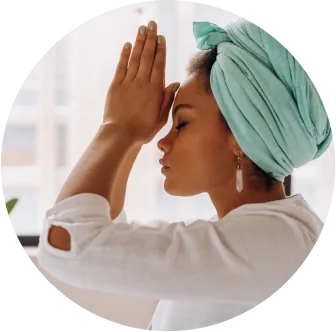 woman's profile wearing rose quartz earrings turquoise headpiece with her hands at prayer at her third eye chakra