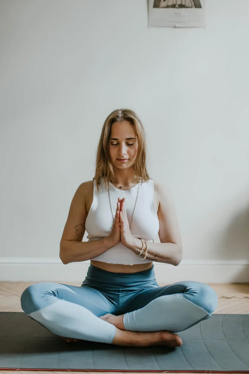 woman meditating at home, lotus pose, hands in prayer, heart chakra open