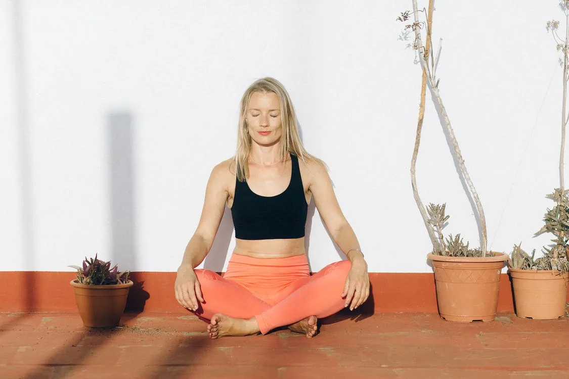 woman in lotos pose meditating and connecting to earth. Clay pots with plants, earthy colors, grounding energy, pachamama
