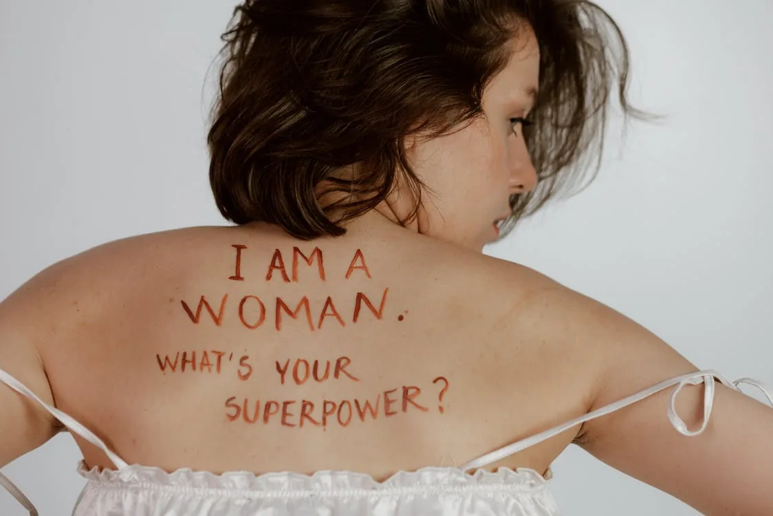 Girl with a writing on her back. I am a woman. What's your superpower?