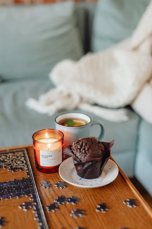 puzzle, chocolate cupcake, mint and lemon tea, burning candle, cozy ambience for practicing mindfulness at home