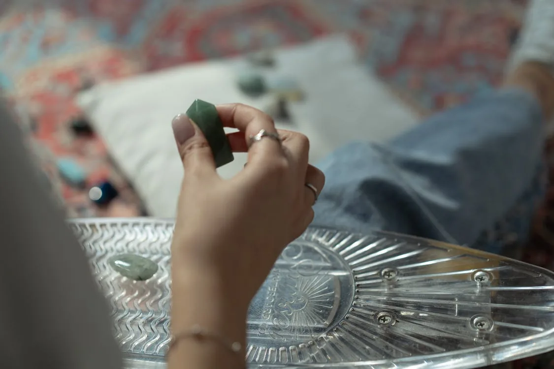 A woman holding green crystal pyramid in her hands. Meditation with healing crystals. 